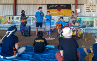 Young interns performing a song for kids sitting on the floor